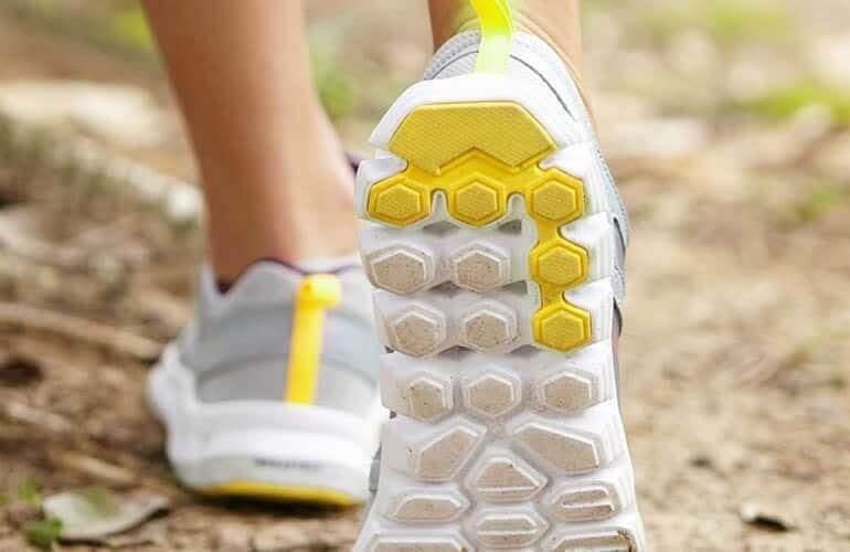 Gros plan sur les chaussures de sport d'une personne marchant sur un sentier.