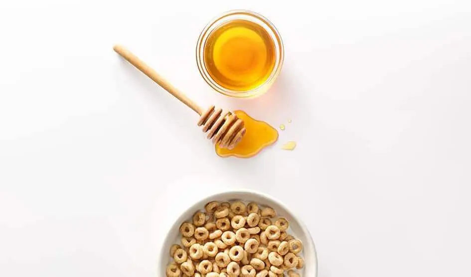 Du miel frais à côté d'un bol de Cheerios