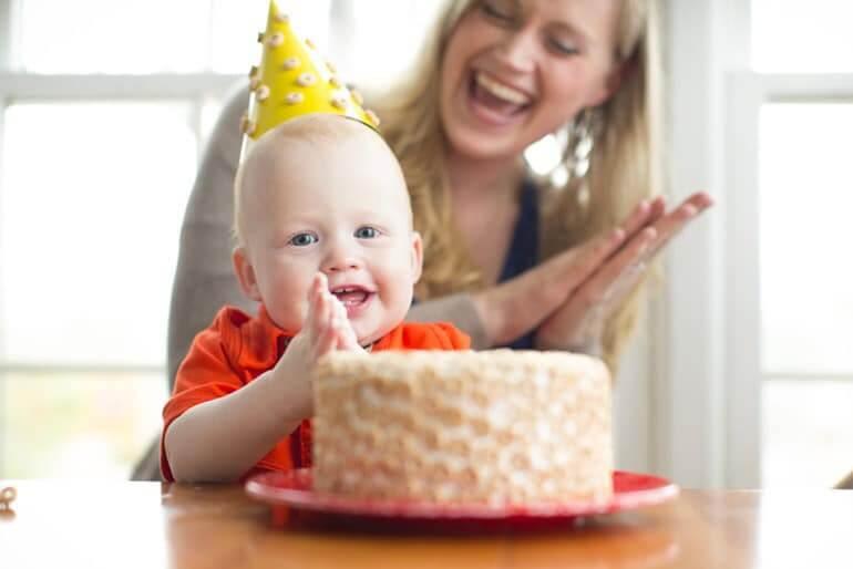 Child with mother clapping & smiling while celebrating with a Cheerios cake.